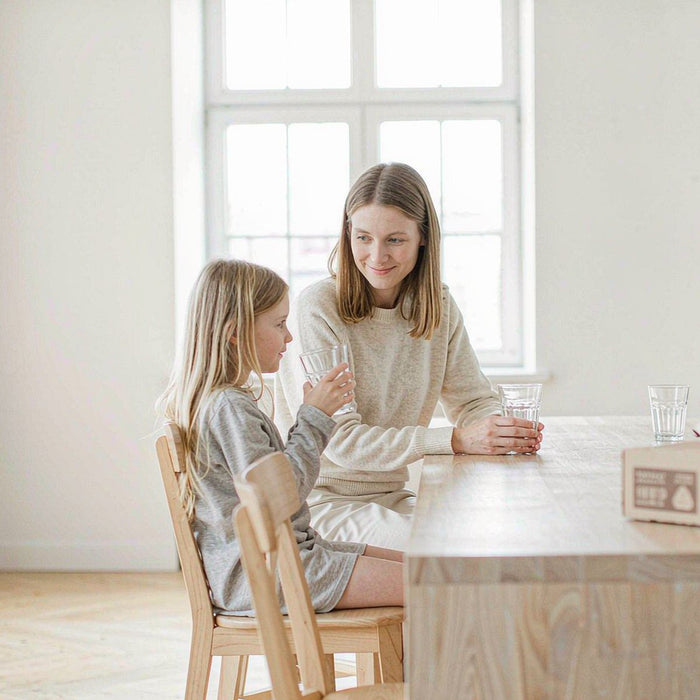 Western mother and daughter at a bright kitchen island with a delivery box, calm morning light