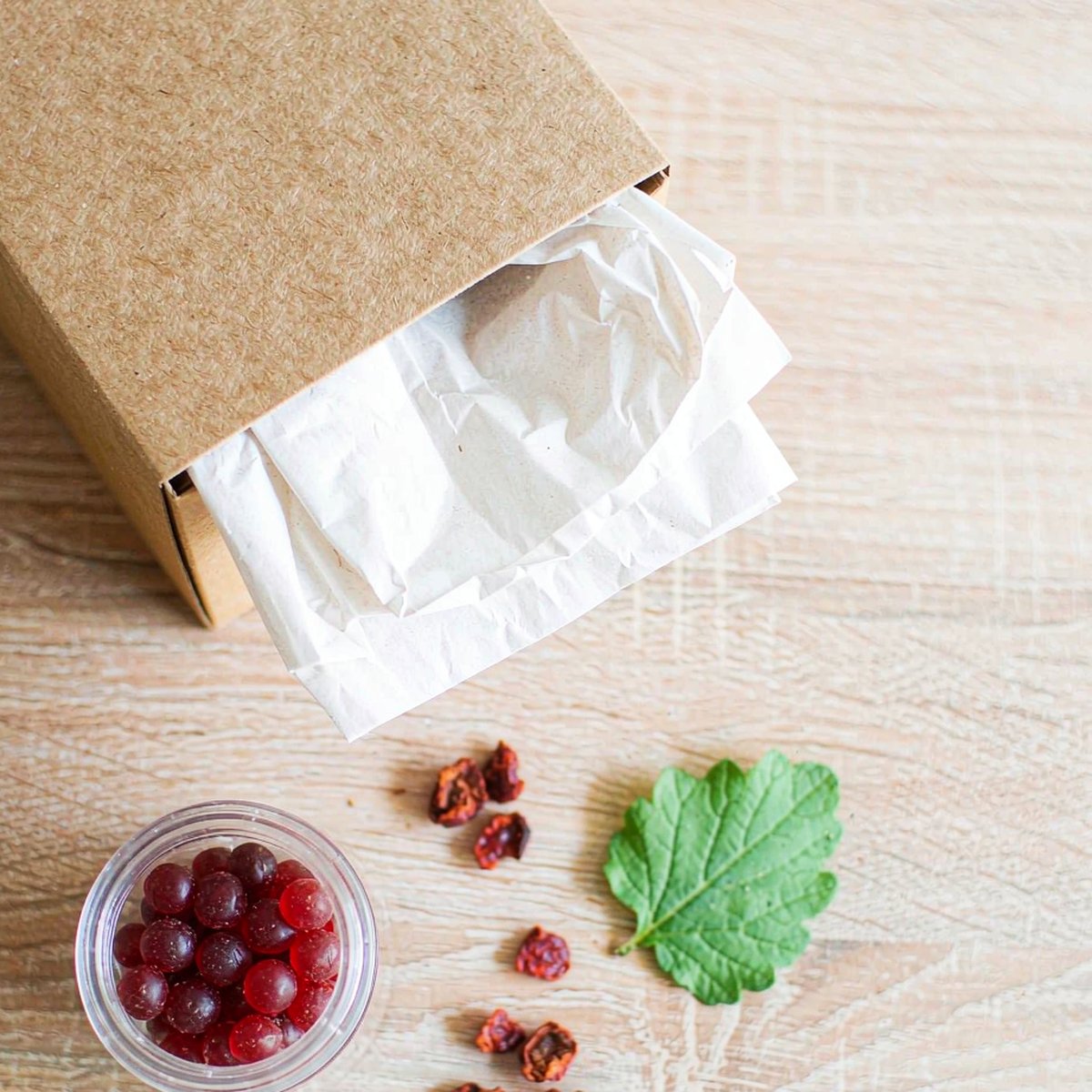 Kraft subscription box and glass jar of berry gummies arranged on a light oak table in morning light