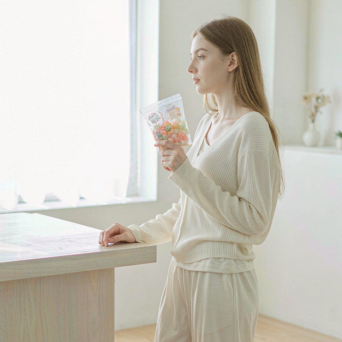 A young Caucasian woman in a bright sunlit kitchen holding a soft pouch of gummies, natural light, airy minimal lifestyle.