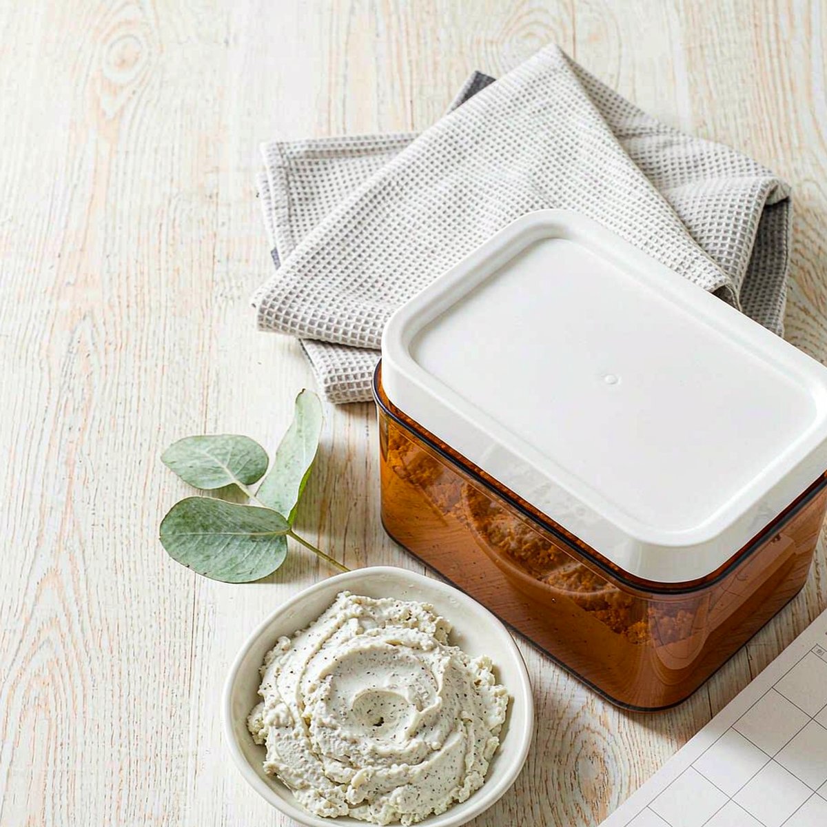 Overhead flat lay of an amber supplement jar, calendar card and eucalyptus on a light oak desk